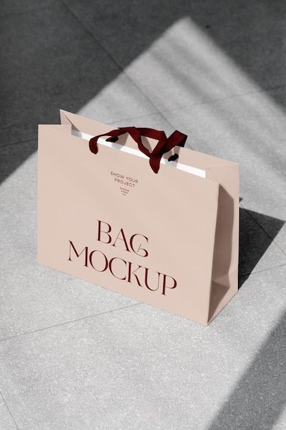 a bag mockup on the ground with a red ribbon tied around it's handle