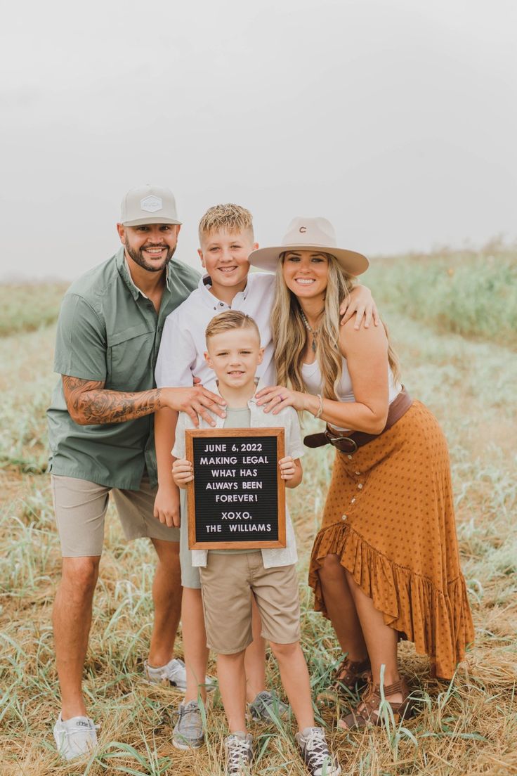 a family posing for a photo in the middle of a field with a sign that says,