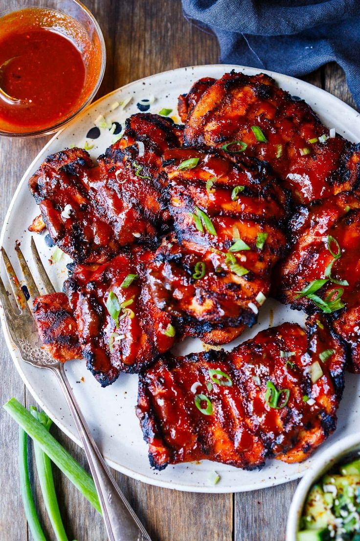 bbq ribs with sauce and green beans on a white plate next to dipping sauce