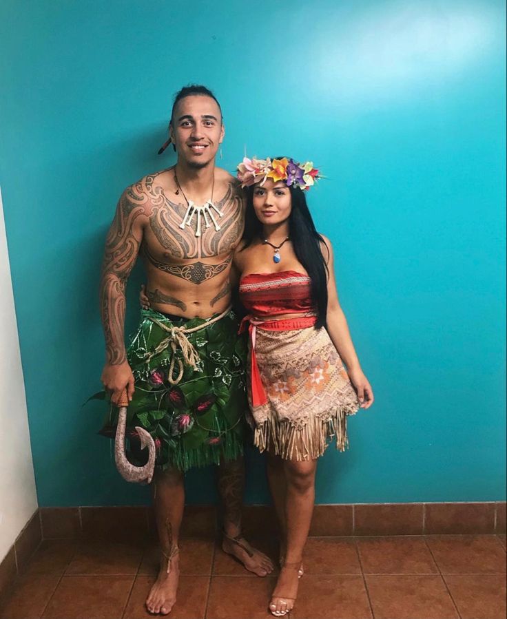 a man and woman dressed up as hula dancers in front of a blue wall