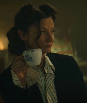 a woman holding a coffee cup in her right hand and looking off into the distance