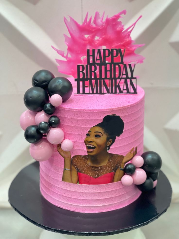 a pink birthday cake with an image of a woman on the top and balloons around it