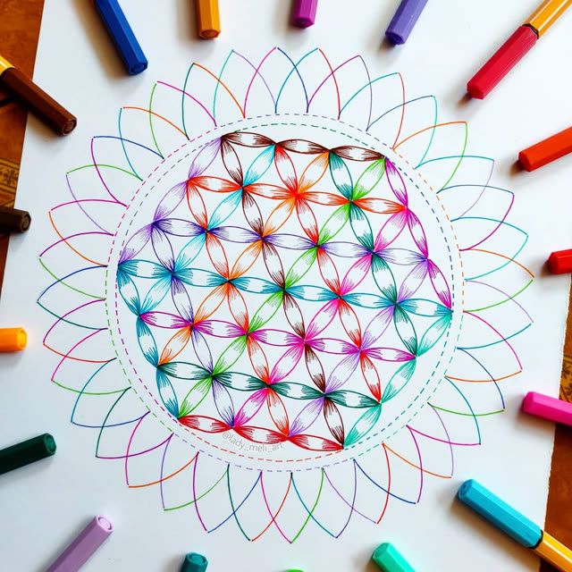 colored crayons surrounding a drawing of a flower with an intricate design on it