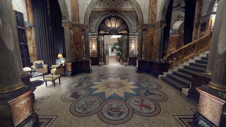 an ornately decorated lobby with stairs and chandeliers on either side of the staircase