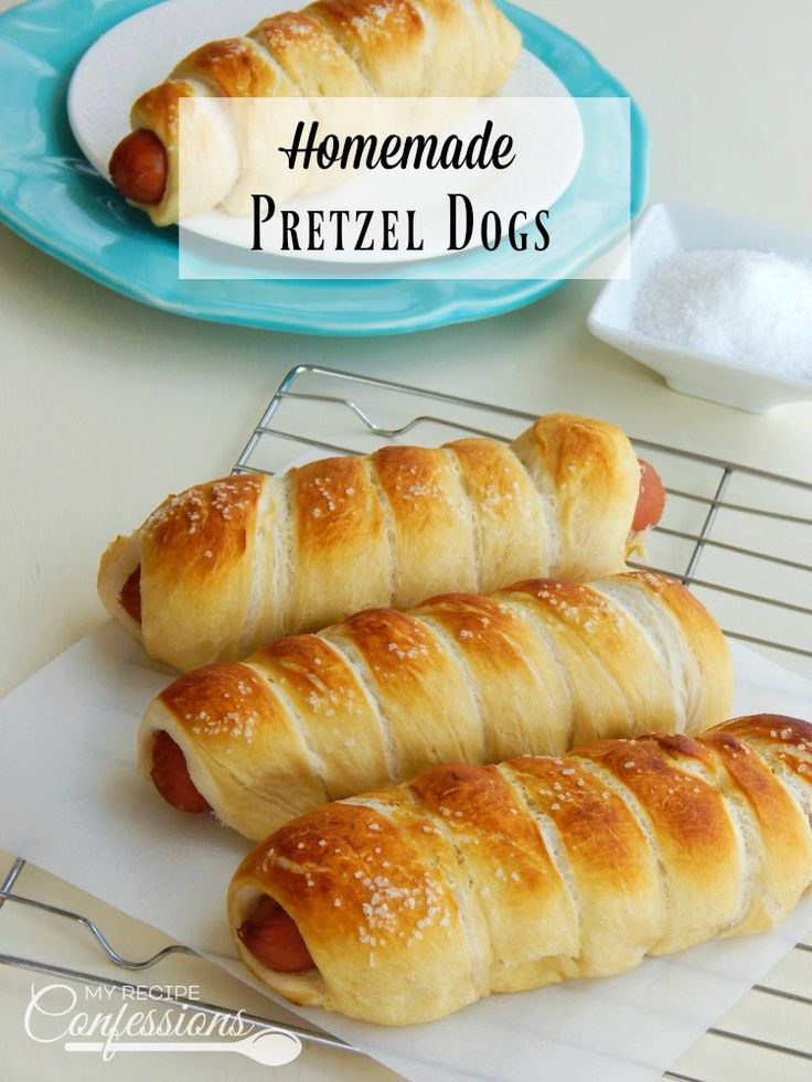 hotdogs wrapped in bread on cooling rack next to plate with powdered sugar