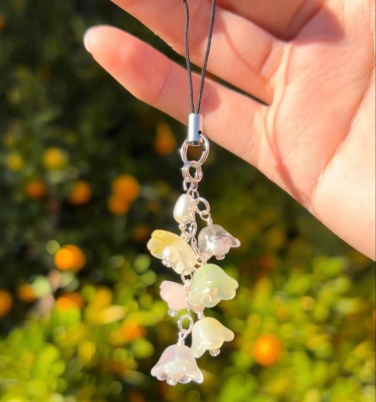 a hand holding a necklace with flowers on it