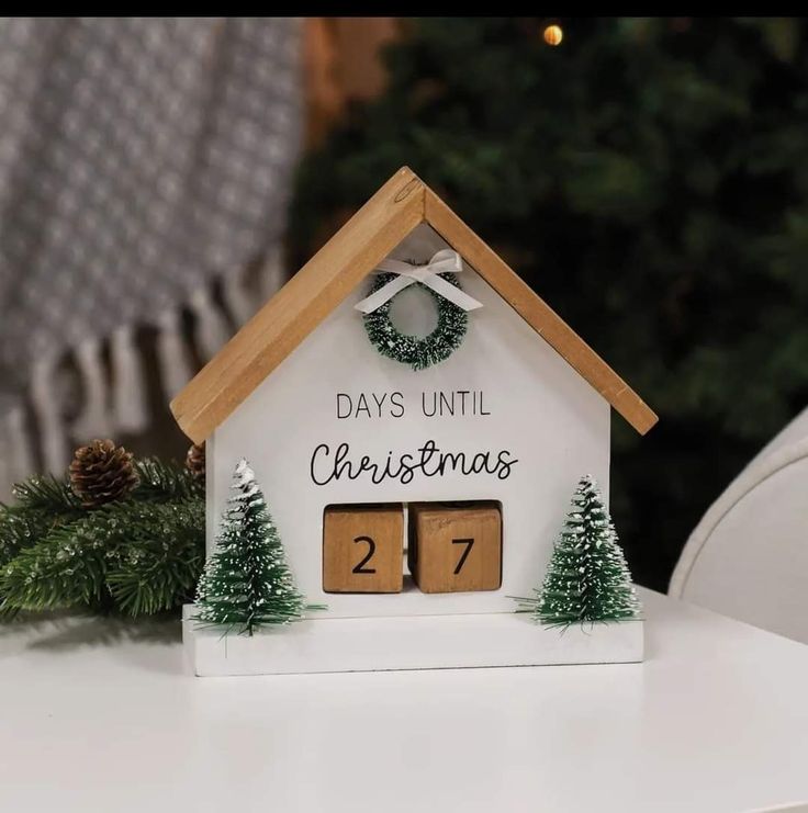 a small white house with christmas decorations on the front and two doors that say days until christmas