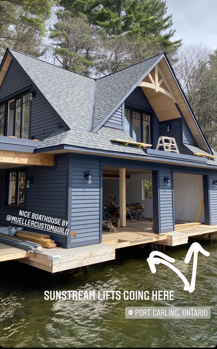 a blue house sitting on top of a lake next to a dock with a ladder