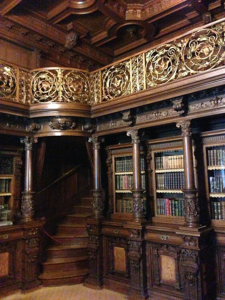 an elaborately carved library with bookshelves and stairs in the center is shown