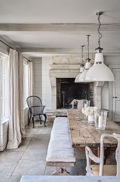 a dining room table with two chairs and a bench in front of the fire place