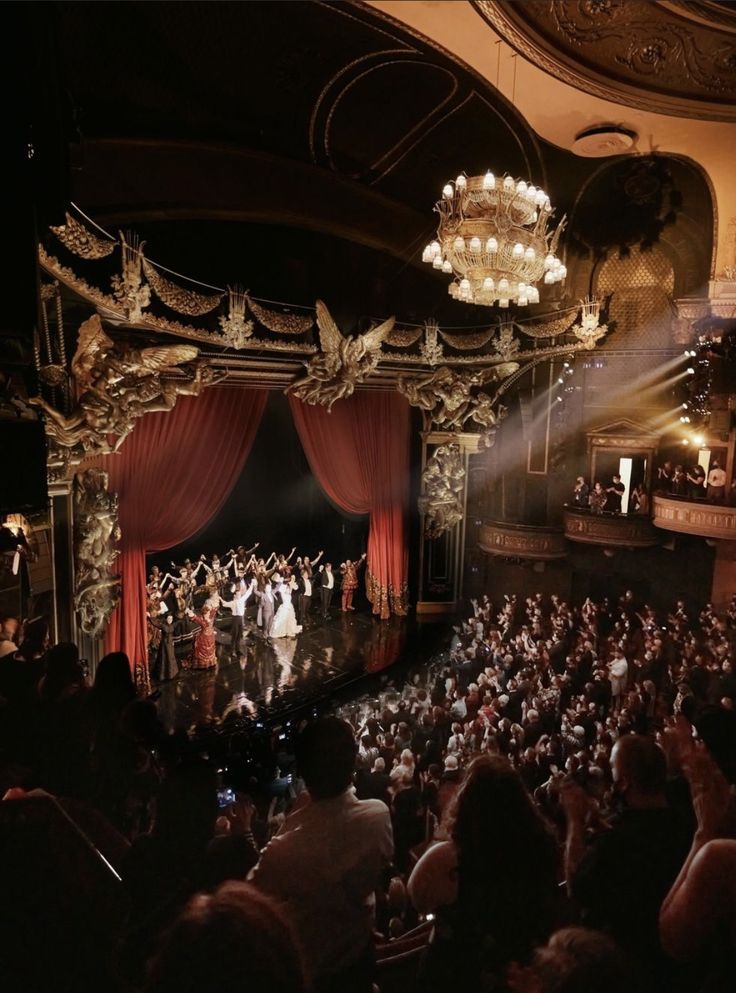 an auditorium full of people with red curtains