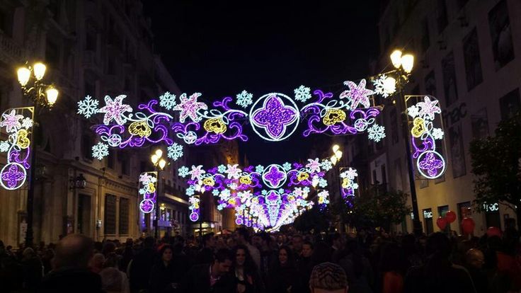 people are walking under an archway decorated with lights