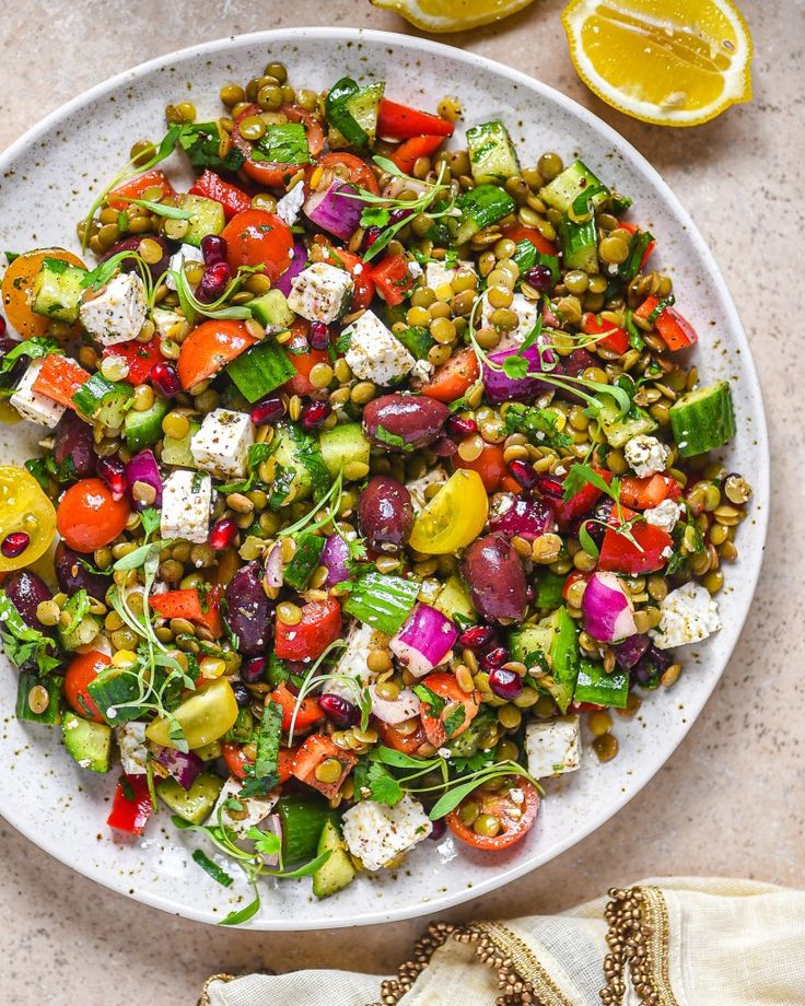 a white plate topped with a salad next to sliced lemons