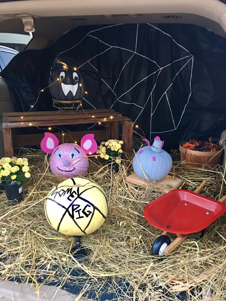 the back of a car with fake animals in it's trunk and some hay