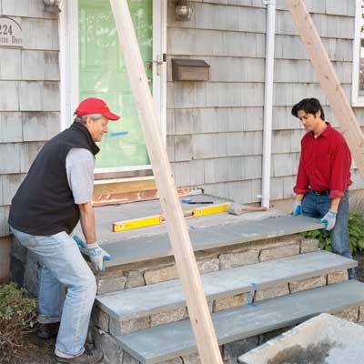 two men standing on steps in front of a house