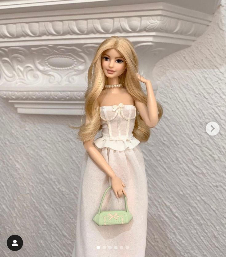 a barbie doll is holding a purse and posing for the camera in front of a white wall