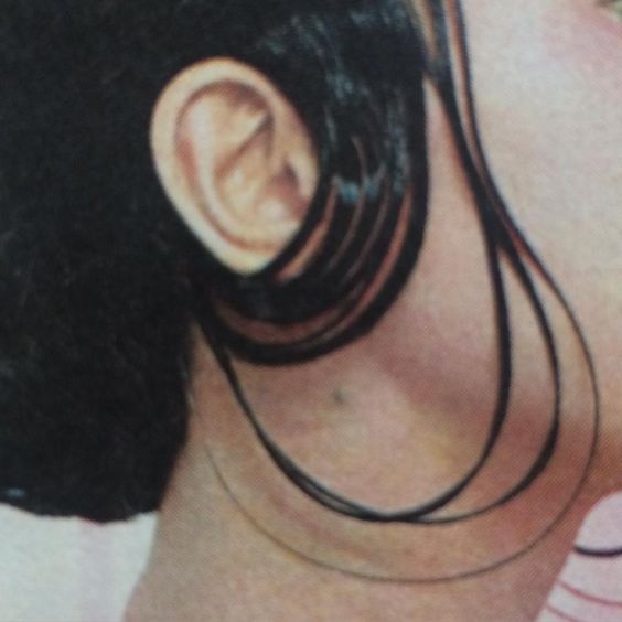 the back of a woman's head with black hair and ear piercings on it