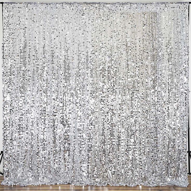 a white curtain with silver sequins hanging from it's side in front of a wooden floor