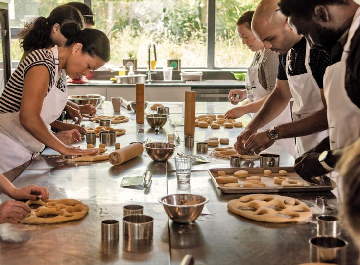 a group of people standing around a table with doughnuts on it