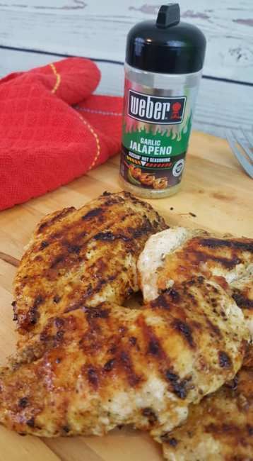 grilled chicken on a cutting board next to a bottle of ketchup