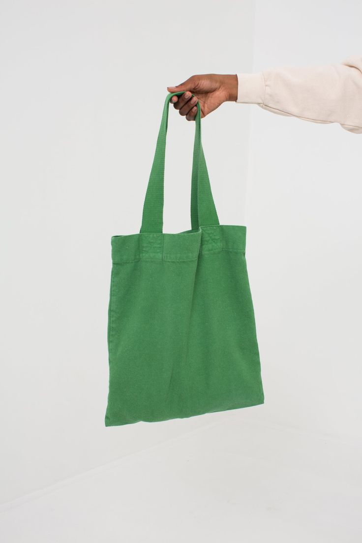 a person is holding a green bag in their left hand and the other hand is pointing at it