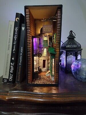 a book shelf with books and a miniature house in it