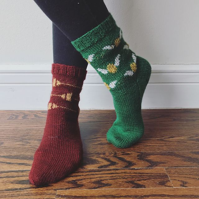 the legs of a woman wearing green socks with red and white designs on them, standing in front of a wall