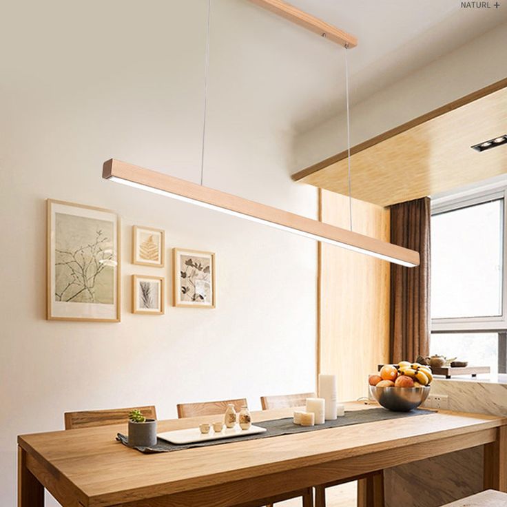 a dining room table and chairs with pictures on the wall behind it in front of a window