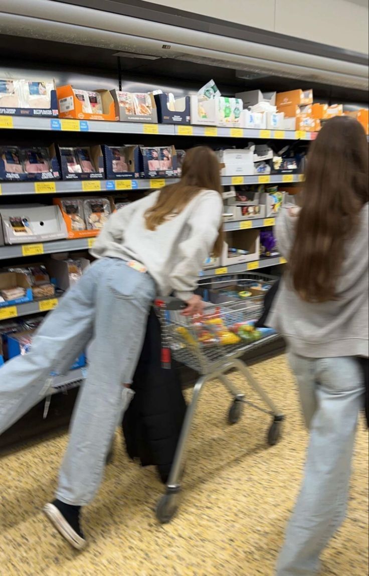 two women pushing a shopping cart in a store