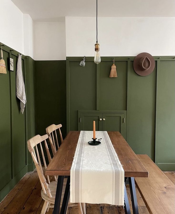 a dining room with green walls and wooden floors, including a table set for four