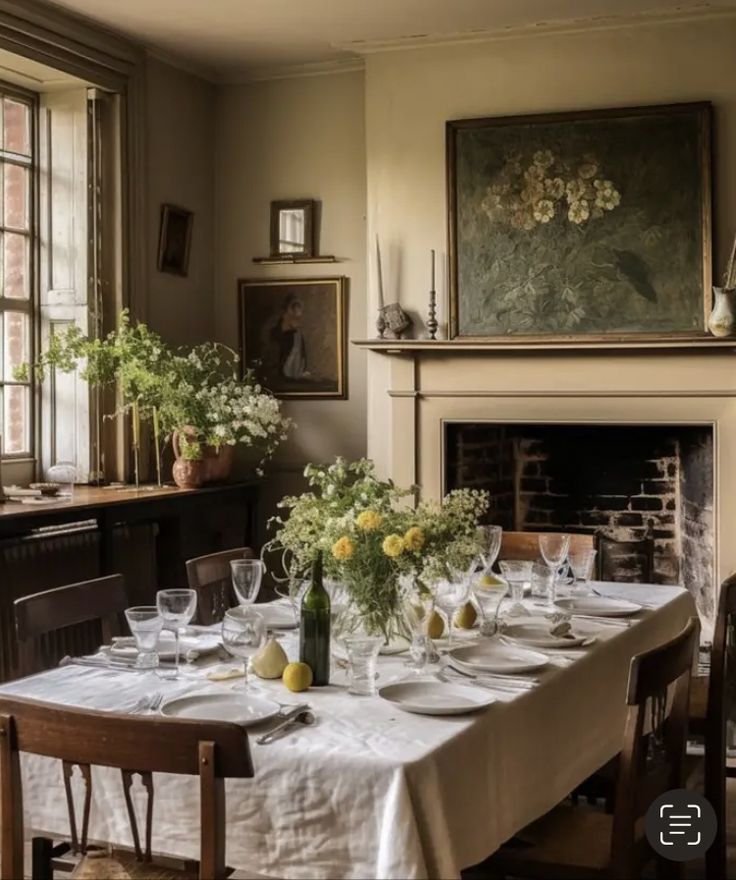 a dining room table is set with white linens and yellow flowers in vases