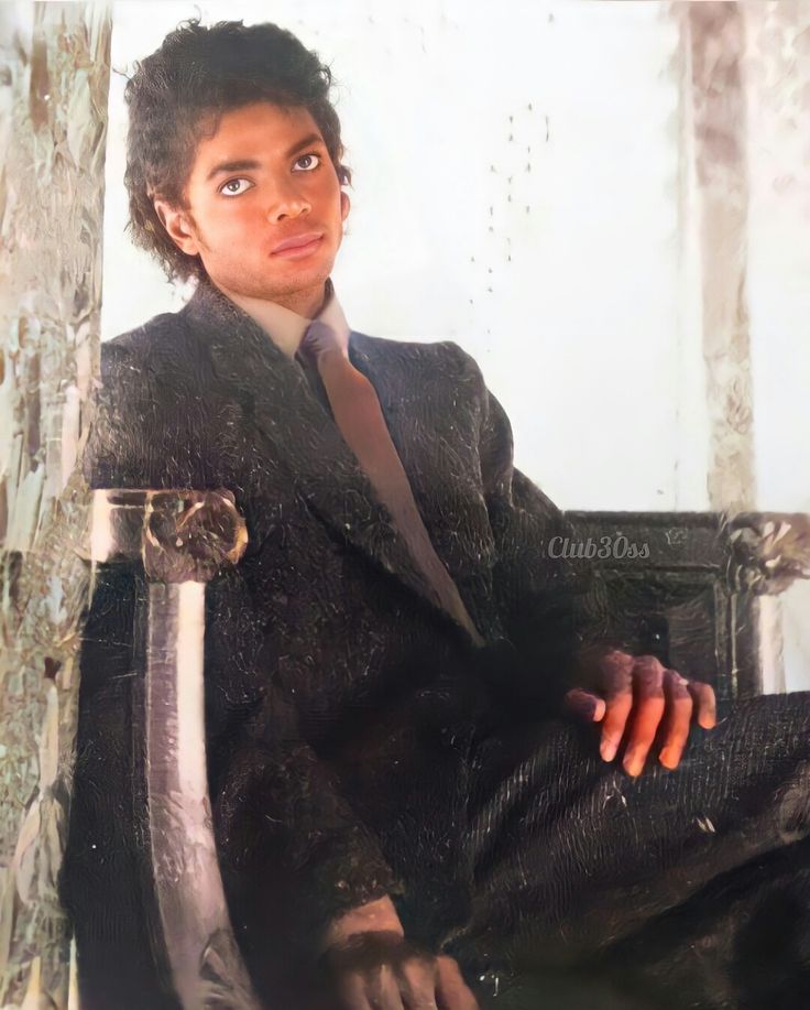 a man sitting in a chair wearing a suit and tie