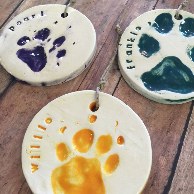 three ceramic ornaments with painted paw prints on them