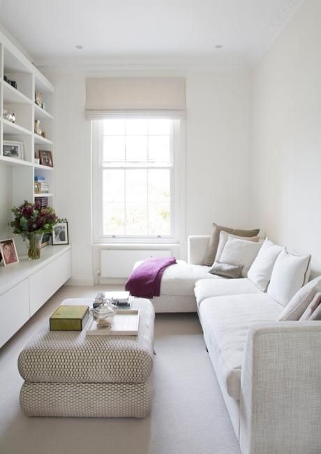 an image of a living room with white furniture and bookshelves on the wall