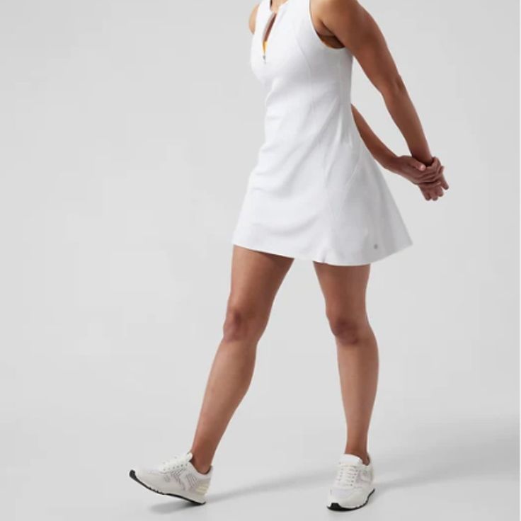 a woman in a white tennis dress is walking