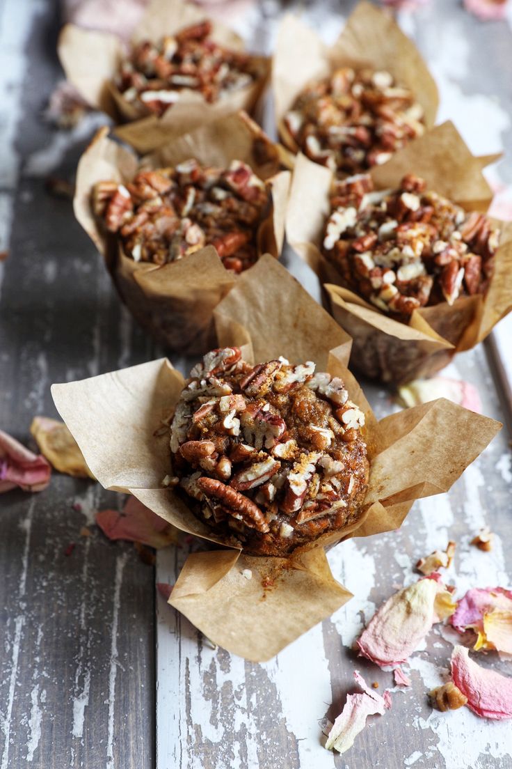 several muffins with nuts and pecans in them on top of a wooden table