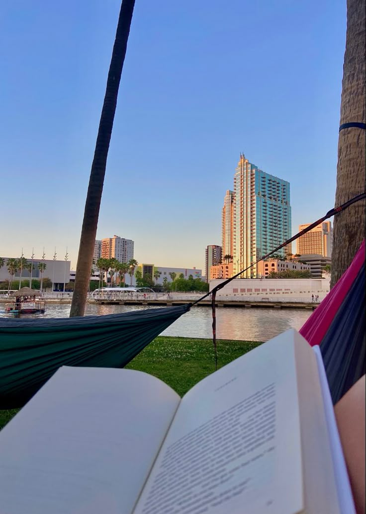 an open book sitting on top of a hammock next to a body of water