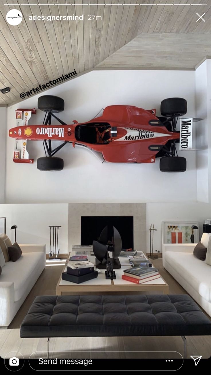 a living room filled with furniture and a race car mounted to the wall above a fire place