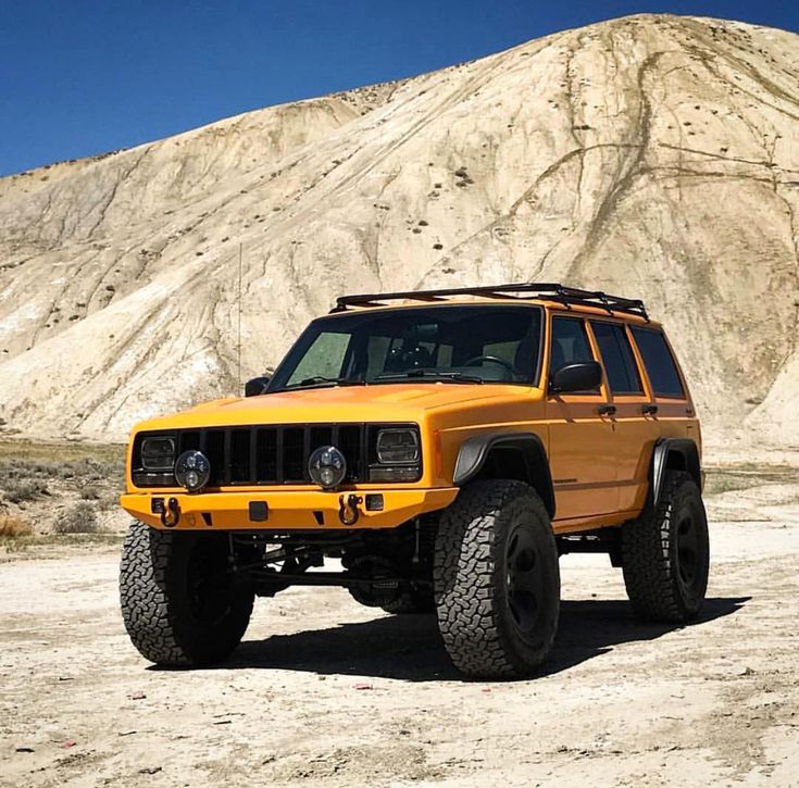 an orange jeep parked in front of a mountain