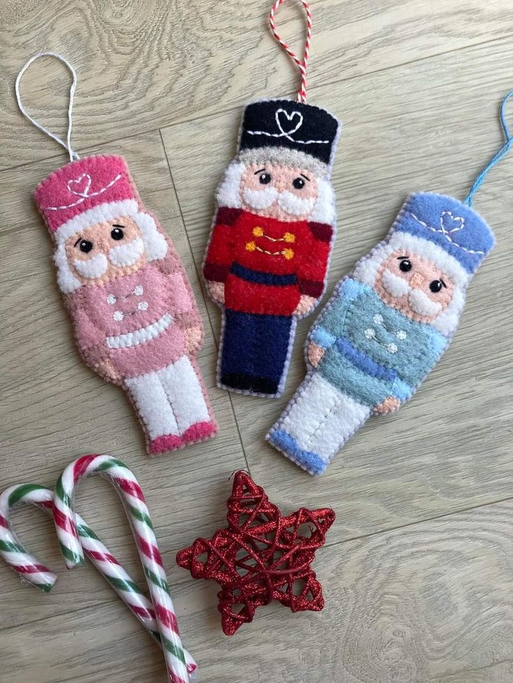 three handmade christmas ornaments on a wooden floor next to candy canes and an ornament