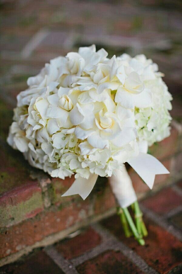 a bouquet of white flowers sitting on top of a brick wall