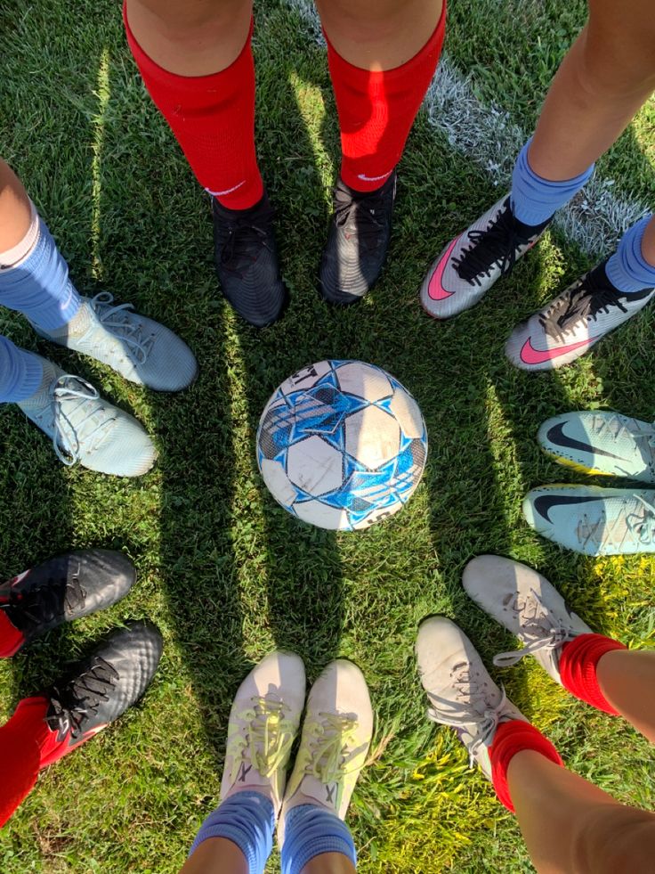 a group of people standing in a circle with their feet on a soccer ball while wearing socks