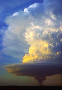 a large cloud is in the sky with some clouds above it and an airplane flying by