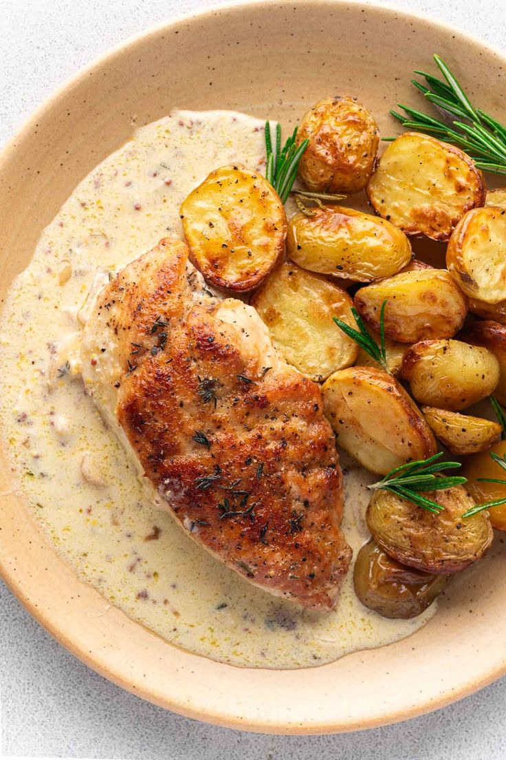 a bowl filled with potatoes and meat on top of a white tablecloth next to a fork