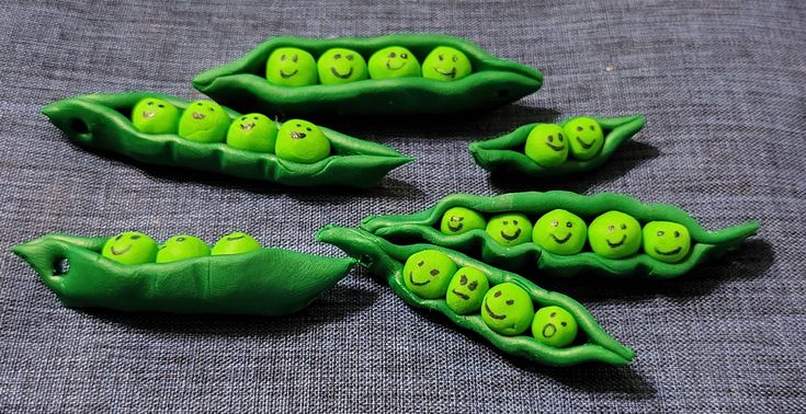 three peas with faces painted on them sitting next to each other in the shape of pea pods