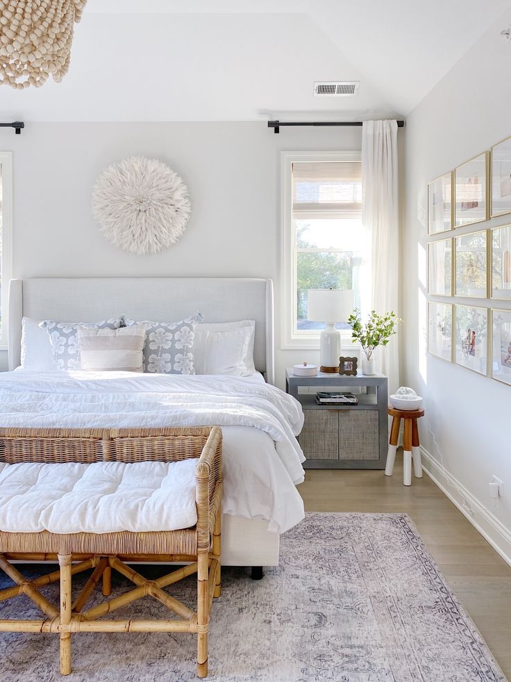 a bedroom with white walls and wood flooring has a large bed in the center