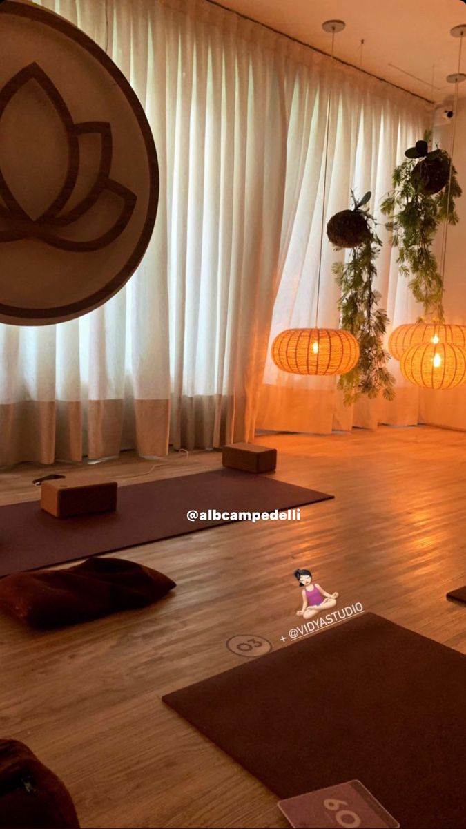 there are many yoga mats on the floor in this room with lights hanging from the ceiling