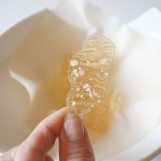 a person holding a piece of food in front of a white bowl on a table