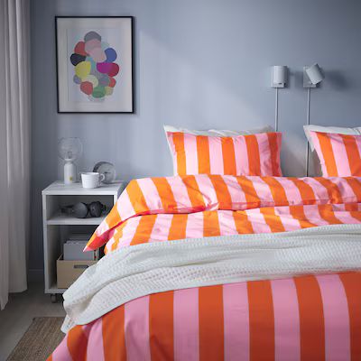 an orange and white striped bed in a bedroom