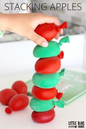 a hand is stacking apples on top of each other